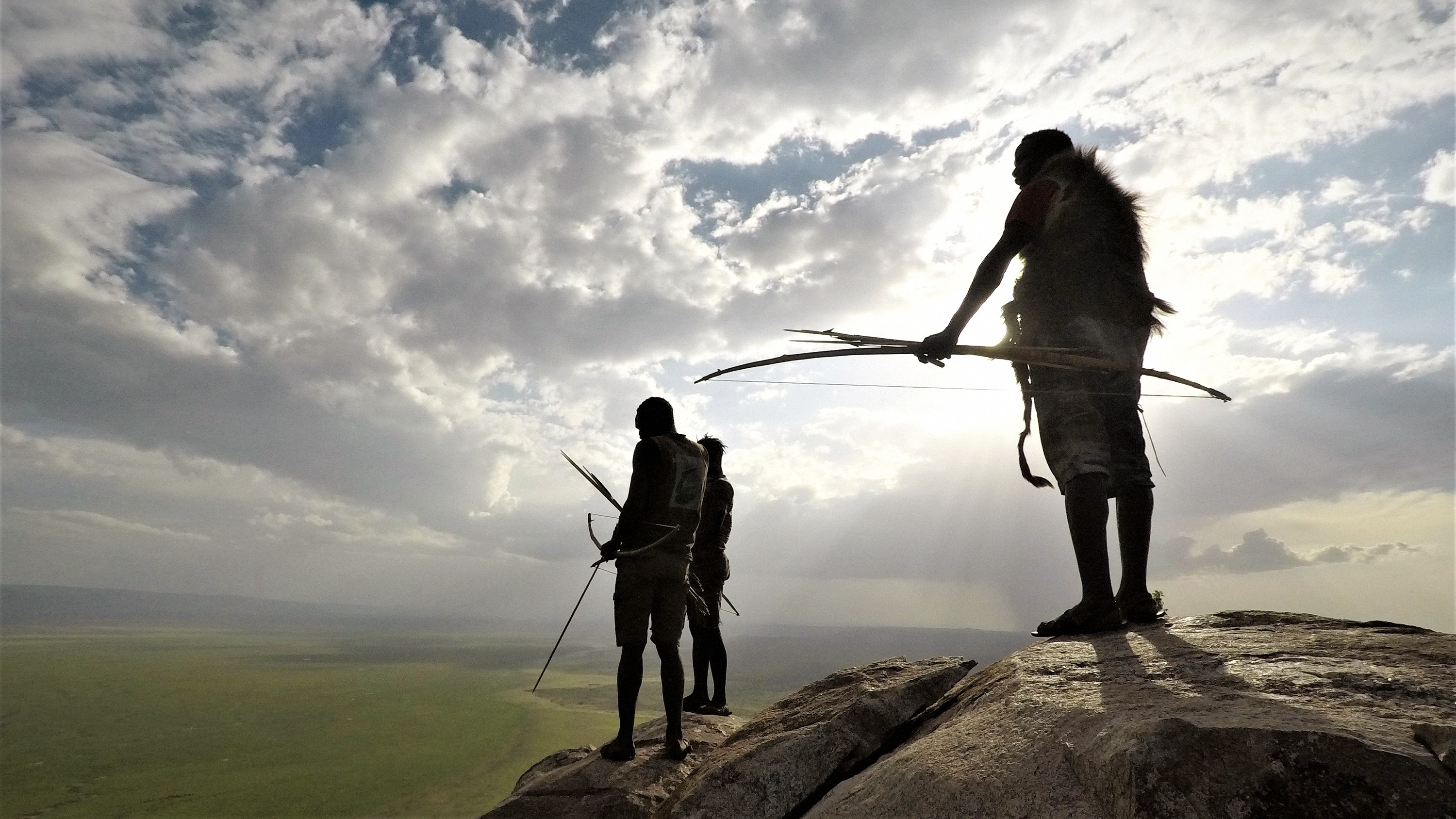 Hadza hunters silhouetted on a kopje at sunset